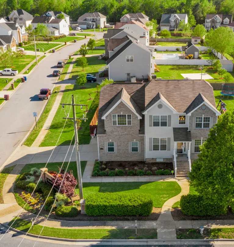 Aerial view of suburban neighborhood with two-story houses, green lawns, and a curved street.