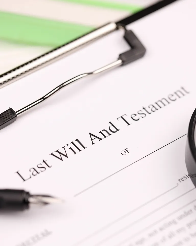 Close-up of a "Last Will and Testament" document on a clipboard with a pen nearby.